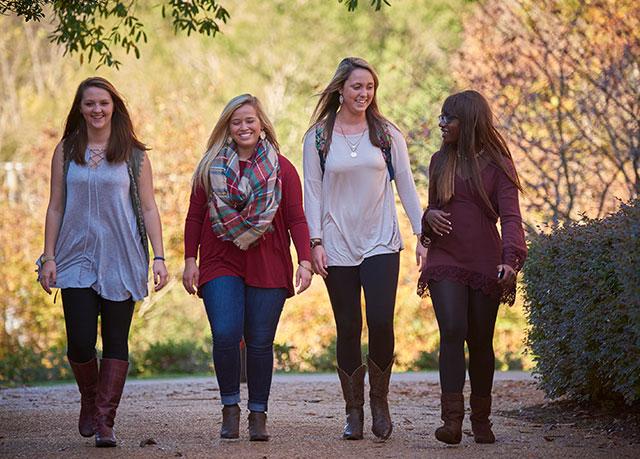 Four female students walk towards the camera on an autumn day