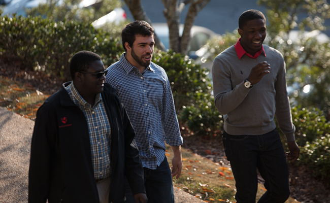 Three young men walk across campus